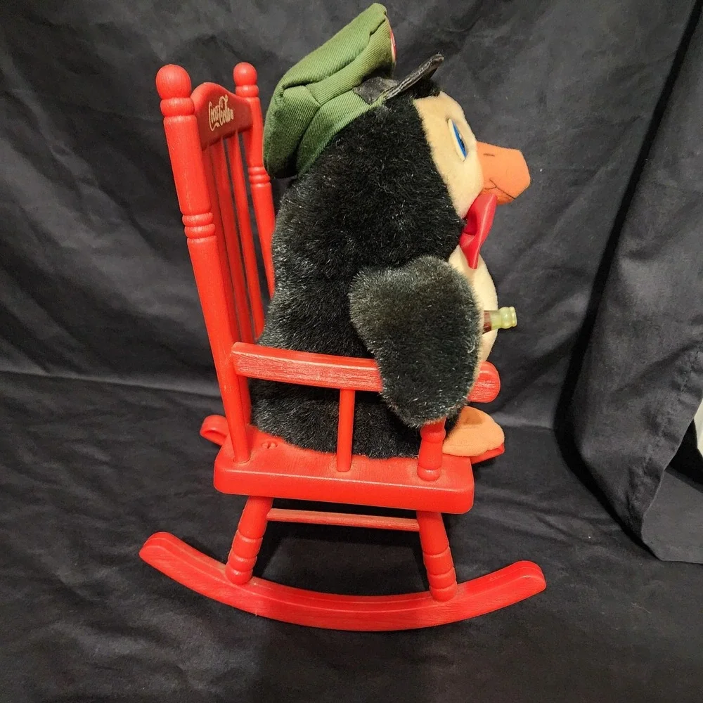 1997 vintage Coca-Cola‎ penguin plush toy sitting in a red rocking chair.
